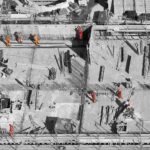 selective color photo of man on top of gray building